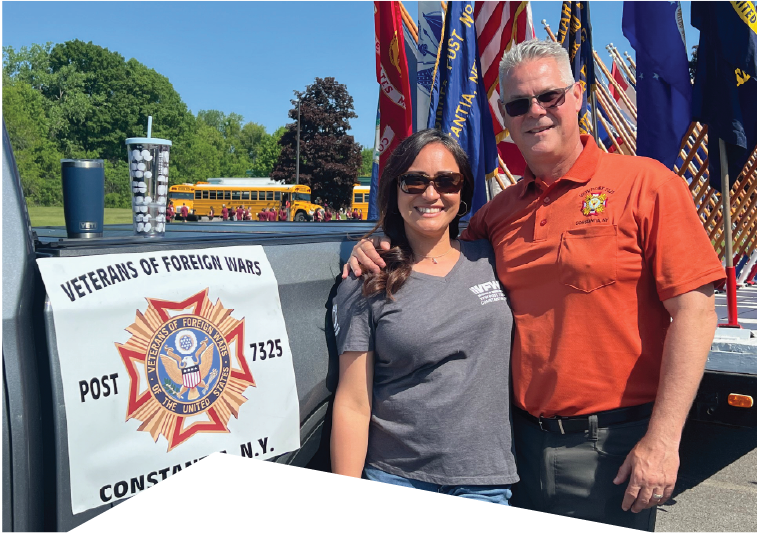 John Mura posing with his wife beside Veterans of Foreign Wars vehicle